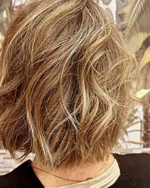 Melena corta a la altura de la nuca, con ondas y mechas rubias